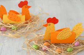 Deux poules en papier et tube d’essuie-tout sur leur nid, avec des œufs en chocolat