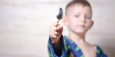 Petit garçon brandissant une cuillère qui brille.