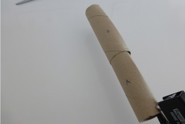 Une personne glisse un tube en carton dans un autre et agrafe les deux extrémités pour créer un tube étroit et solide.