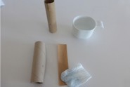 Des tubes en cartons agrafés, un essuie-tout mouillé avec du ruban kraft gommé, et une tasse d'eau
