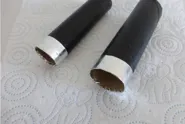 Deux tubes en carton peints en noir dont les extrémités sont couvertes de fines bandes de papier aluminium.