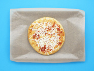 Une pizza à la sauce tomate et au fromage râpé sur une plaque couverte de papier cuisson.