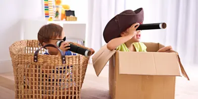 Deux garçons habillés en costumes de pirate qui jouent dans des boîtes en carton et tiennent des longue-vues en carton.