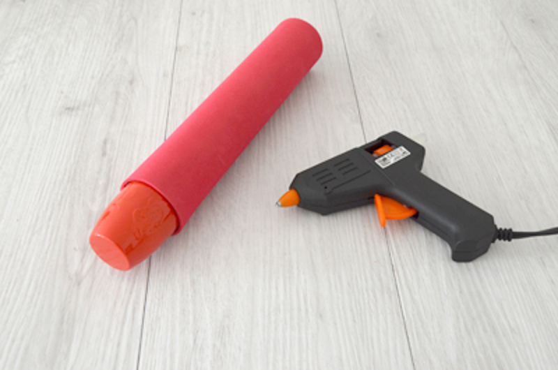 Tube en carton recouvert de mousse rouge grâce à un pistolet à glue.