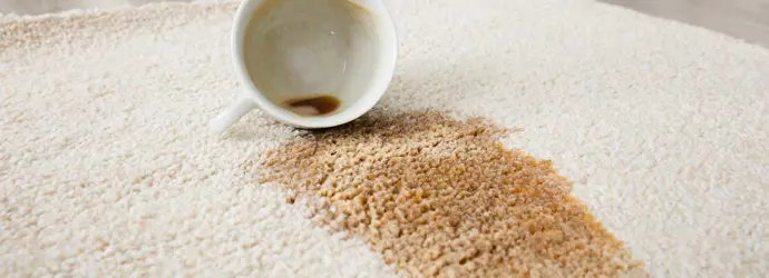 une tasse de café renversée laissant une tache de café sur un tapis écru