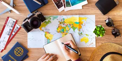 Table sur laquelle se trouvent une carte, un appareil photo, des lunettes de soleil, des billets d’avion et un carnet