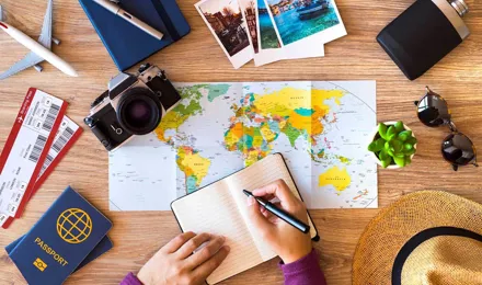 Een tafel met paspoorten, kaarten, zonnebrillen, notitieboekje, vliegtickets en een planner