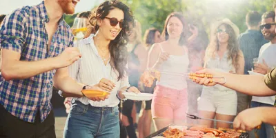 Een groep van vrienden staan op een bbq-feest rondom een ​​bbq-grill