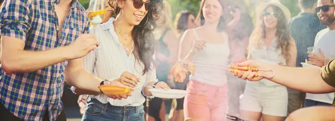 Een groep van vrienden staan op een bbq-feest rondom een bbq-grill