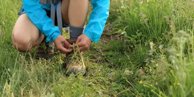 Un enfant attache ses lacets de chaussures de marche