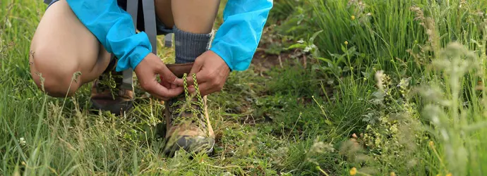 Un enfant attache ses lacets de chaussures de marche