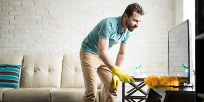 Un homme dépoussière sa maison avec un chiffon
