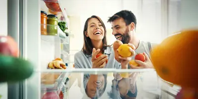 Un couple prend des fruits et des légumes dans le réfrigérateur