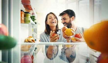 Un couple prend des fruits et des légumes dans le réfrigérateur
