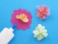 Petites fleurs en papier froissées placées au centre de grandes fleurs en papier, ce qui crée des décorations en 3D.
