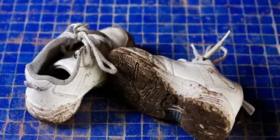 Des baskets boueuses sur un fond bleu carrelé