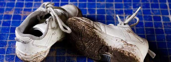 Des baskets boueuses sur un fond bleu carrelé