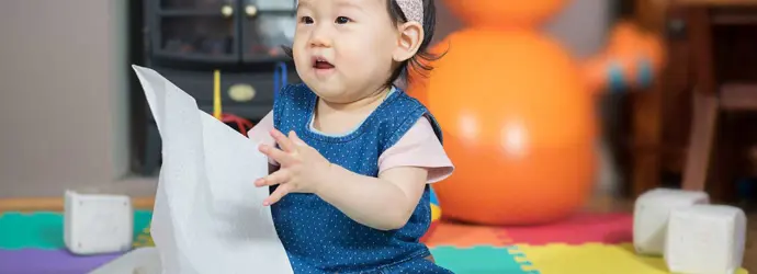 Petite fille portant un jean et un t-shirt rose et tenant une feuille d’essuie-tout dans les mains