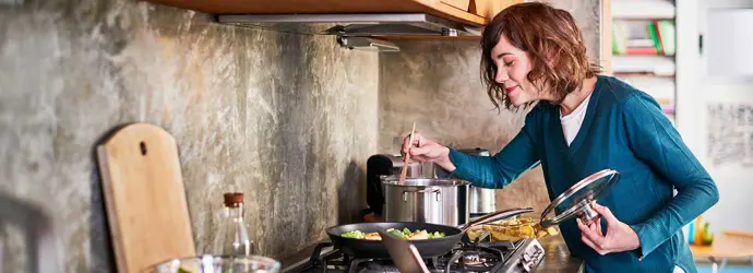 Une femme prépare la nourriture dans une cuisine et fouettant dans une casserole