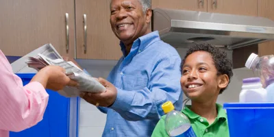 Grand-père apprend à un garçon à recycler dans la cuisine.