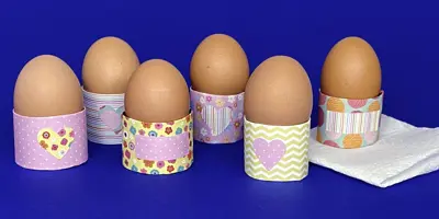 Œufs dans des coquetiers de Pâques personnalisés. Une feuille d’essuie-tout se trouve sous l’un des coquetiers.