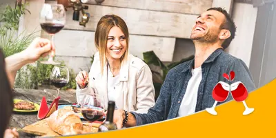 Un groupe d'amis souriants, dégustant du vin et de la nourriture autour d'une table lors d'une garden party.