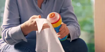 un homme en chemise bleue essuie une bouteille en plastique réfrigérée avec du papier essuie-tout Okay
