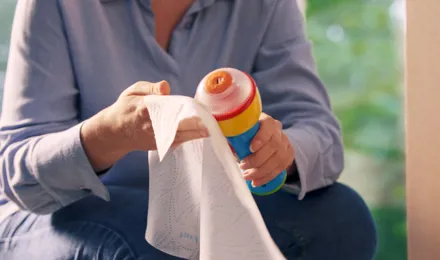 un homme en chemise bleue essuie une bouteille en plastique réfrigérée avec du papier essuie-tout Okay
