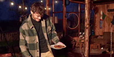 Jeune homme cuisinant sur un barbecue dans le jardin le soir.