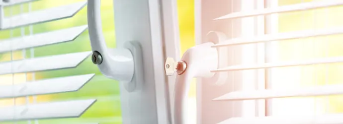 Gros-plan sur une fenêtre entre-ouverte sur laquelle se trouvent des stores blancs.
