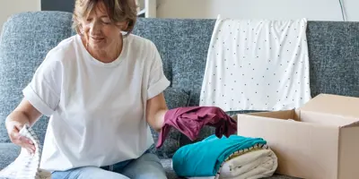 Une femme trie des vêtements dans une boîte dans un salon confortable.