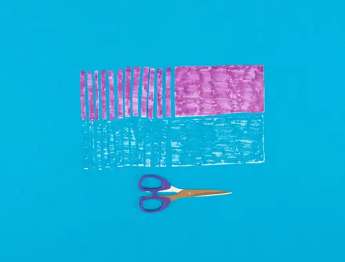 DIY pinata en carton recyclé, étape 12 : faire des franges colorées en découpant et coloriant des feuilles d'essuie-tout