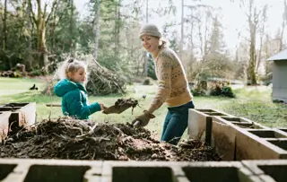 Une femme souriante et un enfant pelletant ensemble du compost.