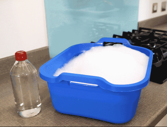 Femme dans des gants en caoutchouc nettoyant la hotte dans la cuisine