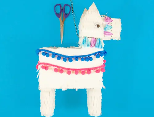 DIY pinata en carton recyclé, étape 14 : décorer la pinata avec les pompons, des ficelles et des yeux