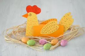 Poule en papier et tube d’essuie-tout sur son nid, avec des œufs en chocolat