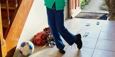 Jeune fille entrant dans la maison par la porte et tachant le sol avec ses chaussures sous le regard de sa grand-mère.