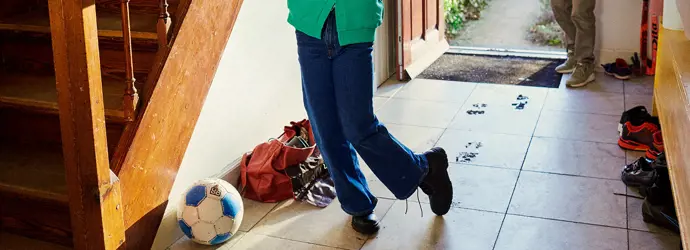 Jeune fille entrant dans la maison par la porte et tachant le sol avec ses chaussures sous le regard de sa grand-mère.