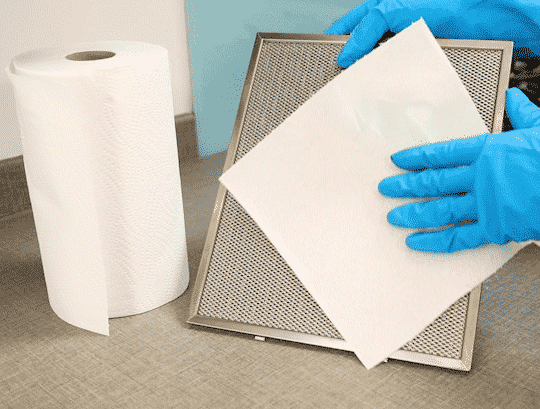 Femme dans des gants en caoutchouc nettoyant la hotte dans la cuisine